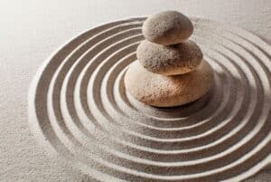 zen garden with circles drawn in sand and a pyramid of three little stone at the center