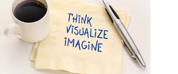 Words written on a pale yellow napkin, Think, Visualize, Imagine, with a cup of coffee and an open pen set on top of napkin