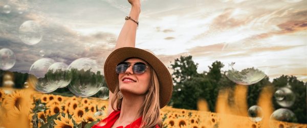woman-surrounded-by-sunflowers-raising-hand-1261459